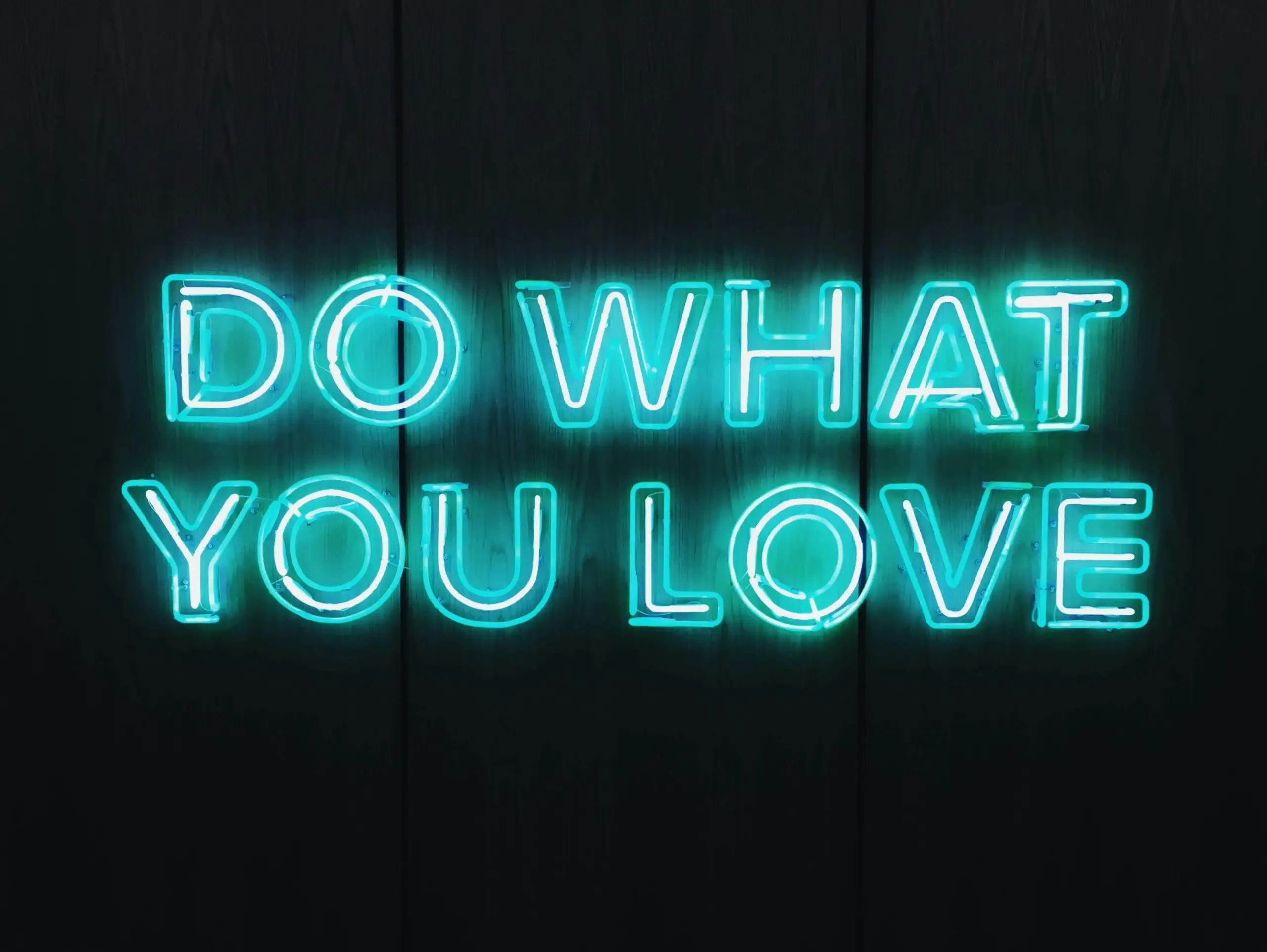 Neon blue sign on a dark background displays the words DO WHAT YOU LOVE.